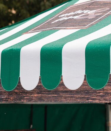Close-up of a folding gazebo roof with green and white stripes and wood-look design.